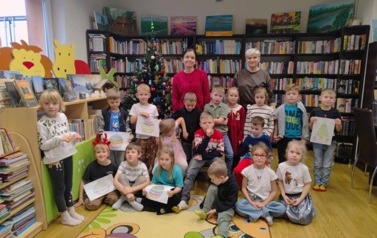 Grupa dzieci przy choince jest razem ze swoją Panią i z bibliotekarką.