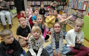 Dzieci siedzą na dywanie i słuchają bajki