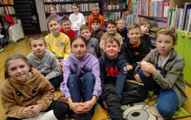 Dzieci siedzą w grupie na dywanie i słuchają opowiadania.