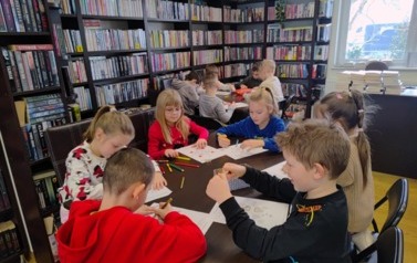 Dzieci przy stołach kolorują hafty i stroje kociewskie.