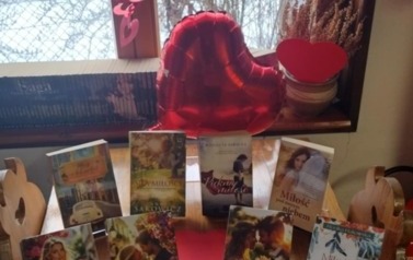 Na stole w bibliotece w Borzechowie są wyłożone książki o miłości. Za nimi leży balon w kształcie serca i pomiędzy książkami leżą serca cerwone z papieru.