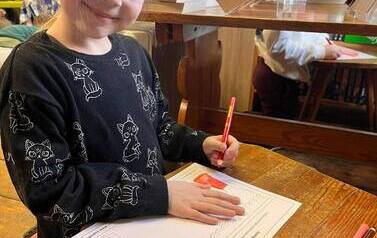 Dziewczynka w blond wlosach na kartce rysuje siebie w teatrze w wymarzonej roli.