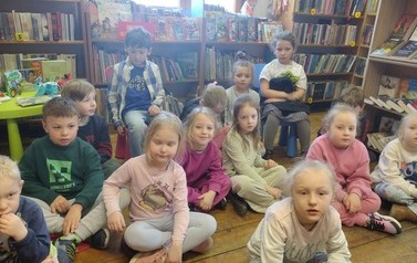Dzieci siedzą na siedziskach i słuchają bajki.