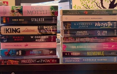 Na stole w dw&oacute;ch rzędach są ułożone nowe książki z widocznymi tytułami na grzbietach
