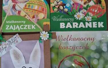 Na stole są położone trzy książeczki o tytułach: " Wielkanocny zajączek", Wielkanocny baranek", "Wielkanocny koszyczek" i życzenia z zajaczkiem od dzieci.