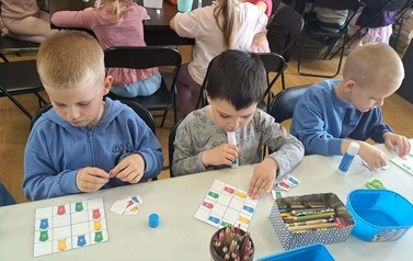 Troje chłopc&oacute;w dopasowuje na sudoku w jakie miejsca wkleić odpowiednie kosze do śmieci