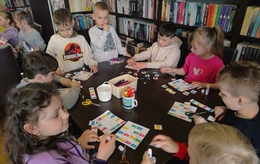 Dzieci przy stole wyklejają sudoku czyli w odpowiednie miejsca naklejaja kolorowe kosze na śmieci aby w pionie i w poziomie sie nie powtarzały.