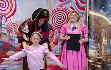 Zosia stoi trzymając Księgę marzeń, obok Pirat "Bigos" trzyma za ramona dziewczynkę z publiczności, kt&oacute;ra ma rozłożone ręce do publiczności.