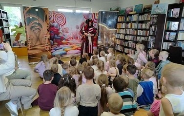 Na dywanie siedzi duża grupa dzieci i patrzą w stronę Pirata, kt&oacute;ry trzyma sieci. Kurtyna przedstawiająca słodycze.