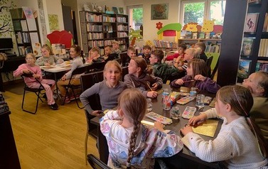 Dzieci siedzą przy trzech stołach i malują farbkami serduszka z gipsu