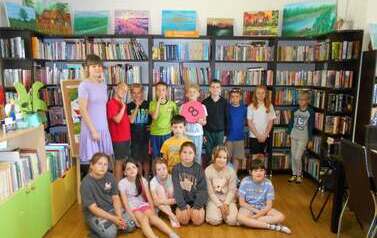 Dzieci stoją w grupie z bibliotekarką