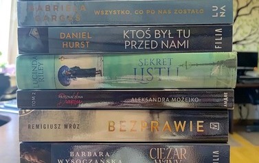 Na stole są wyłożone nowości wydawnicze z widocznymi tytułami