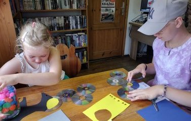 Dwie dziewczynki tworzą pracę plastyczną przy pomocy płyt CD