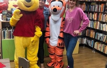 Pani bibliotekarka stoi z Panią, kt&oacute;ra czytała bajkę i z Kubusiem Puchatkiem i Tygyskiem