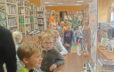 Dzieci stoją w kolejce przy biurku.