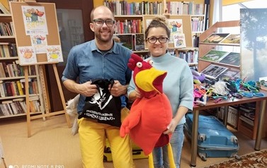 Bajkopisarz stoi z  Panią bibliotekarką, kt&oacute;ra trzyma dużą makotkę kurę