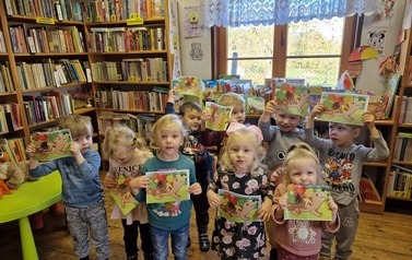 Dzieci stoją w grupie i pokazują swoje prace z wyklejonymi jeżykami.