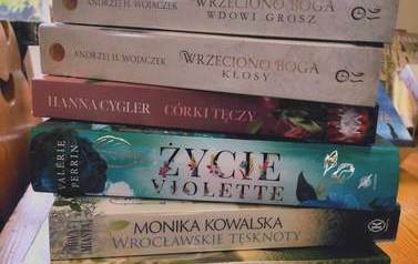 Pionowo ułożone książki na stole z widocznymi tytułami.