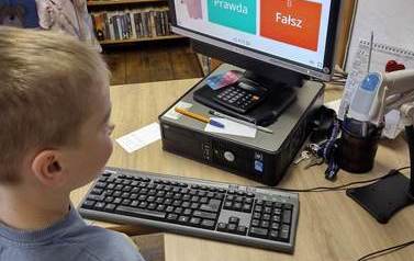 Chłopiec stoi przy komputerze i rozwiązuje test o misiach prawda fałsz.