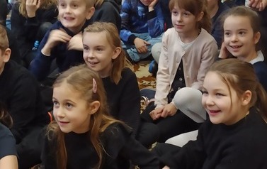 Uśmiechnięte twarze dzieci oglądają teatrzyk.