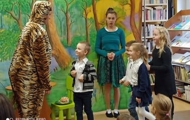 Czw&oacute;rka dzieci stoi przy dziewczynie i tygrysku. Widać publiczność dziecięcą