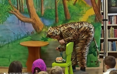 Tygrysek nachyla się nad krzesełkiem na kt&oacute;rym leży tort i posypuje go pieprzem.