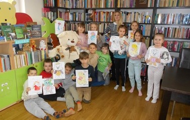 Zdjęcie grupowe dzieci i nauczyciela, dzieci trzymają w rękach prace pokolorowanych misi&oacute;w. W gupie widać misia.