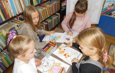 Dziewczynki siedzą przy stoliku i kolorują misie