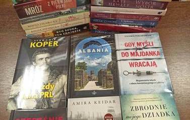 Nowe książki położone na stoliku poziomo gdzie widoczne są okładki i pionowo gdzie widoczne są tytuły.