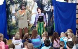 Na tle g&oacute;r skalistych stoi aktor i aktorka, kt&oacute;ra jest lekko pochylona i ma głowę odchyloną do tyłu jakby miała zemdleć. Publicznośc dziecięca jest zainteresowana  i patrzy z zaciekawieniem.