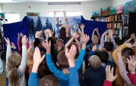 Bałwanek z przodu tańczy, a dzieci Go naśladują.Mają wszyscy ręce w g&oacute;rze.