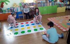 Czw&oacute;rka dzieci ma rozłożone na podłodze grę WYGIBAJTUS i w nią grają.