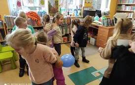 Pięć par dzieci stojących do siebie plecami i ze złączonymi rękoma. Jedna z dziewczynek trzyma niebieski balon.