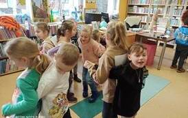 Dzieci tańczą w parach złączeni za ręce i plecami do siebie.