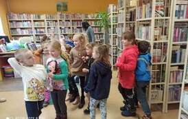 Dzieci stoją w bibliotece w rozsypce.