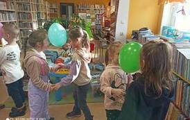 Dwie pary dziewczynek tańczących i trzymających się za ręce,a głowami wsp&oacute;lnie trzymają balonik.