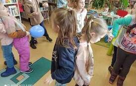 Pięć par dzieci  w tańcu ustawionych do siebie plecami. Jedna dziewczynka trzyma w ręku niebieski balonik.