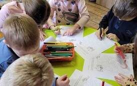 Dzieci przy okrągłym stoliku zaznaczają na kartce drogę w labiryncie do chorej babci.