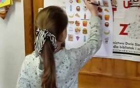 Dziewczynka zaznacza zdrowe produkty dla chorej babci na kartce przyczepionej do drzwi.