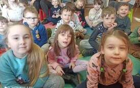 Grupa dzieci siedząca na karimatach podczas słuchania bajki.