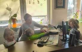 Troje dzieci stoi przy biurku,a bibliotekarka pomaga chłopcu przyłożyć książkę do czytanika.