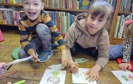 Dziewczynka z chłopcem siedzą na podłodze i kolorują obrazek.