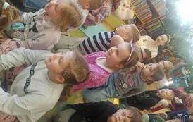 Grupa dzieci siedzących na dywanie.