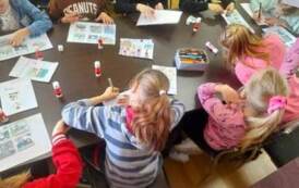 Dzieci przy stole układają historyjkę obrazkową o powstawaniu książki, na stole leżą kleje do jej przyklejenia.