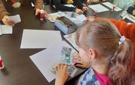 Dziewczynka przy stole układa historyjkę obrazkową o etapach powtawana książki.