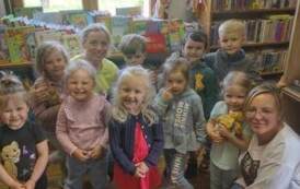 Grupa małych dzieci w bibliotece pozują do zdjęcia wraz ze swoją Panią.