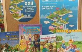 Na tablicy korkowej jest przyczepiony plakat i folder akcji "Cała Polska czyta dzieciom", a niżej oparte na tablicy są książki z bajkami dla dzieci.