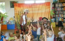 Aktorzy przebrani za Indian zapraszają dzieci do zabawy. Widać dziecięce ręce wyciągnięte w g&oacute;rę.