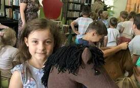 Grupa dzieci stoi po zakończeniu teatrzyku, jedna z dziewczynek trzyma na kiju konika.