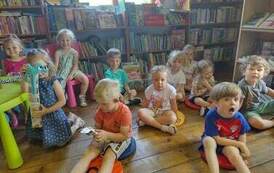 Dzieci siedzą na siedziskach i słuchają bajki.